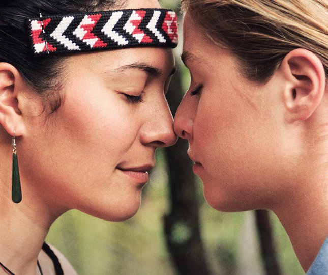 Two people press their noses together in a traditional Maori hongi greeting